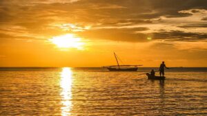 západ slunce nad Indickým oceánem, ve kterém projíždí rybářská loď z pláže Nungwi na Zanzibaru