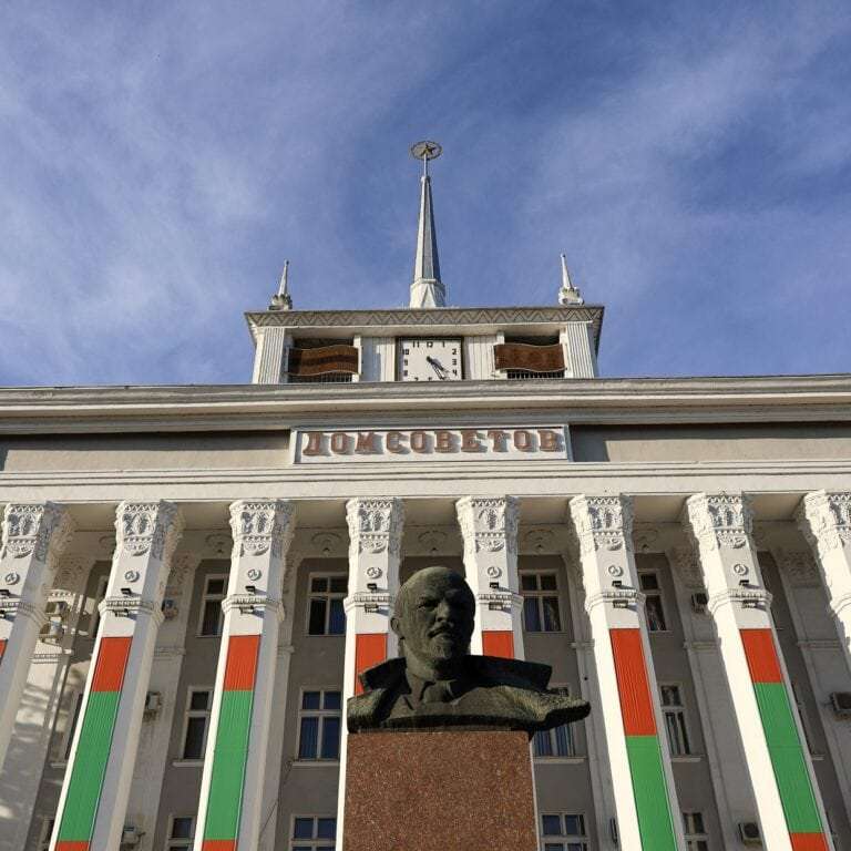 čelní strana budovy s nápisem Dom Sovetov s národními barvami červenou a zelenou na fasádě domu, s bustou V.I.Lenina v popředí