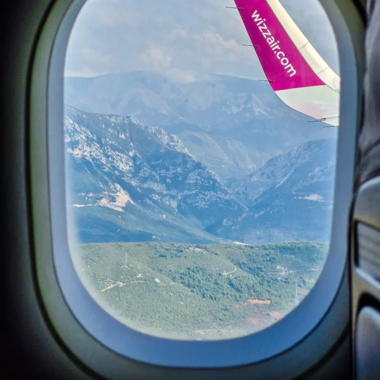 výhled z okna letadla na křídlo letadla WizzAir a albánské hory v pozadí