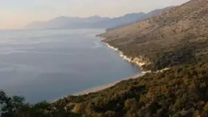 Pohled z výšky na pláž Krorëz obklopenou horami a zelení, moře Albánie