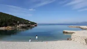 dvě malé děti hrající si s kamínky na pláži Augusto v The Last Bay v Ksamilu v Albánii
