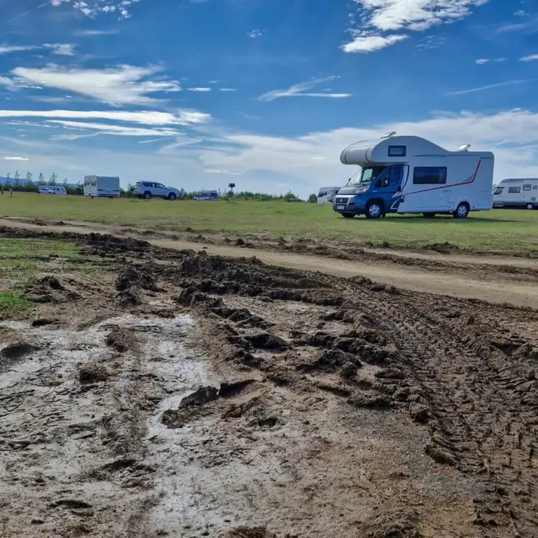 Rozbahněná cesta k kempu na Islandu s obytným autem a islandskou krajinou po dešti.
