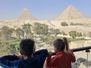 děti se dívají s terasy hotelu na areál pyramid v Gíze