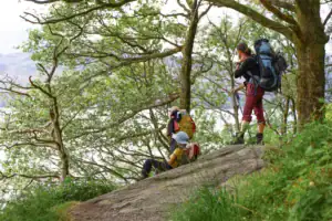 Turisté s velkými batohy odpočívají na břehu jezera Loch Lomond během přechodu West Highland Way