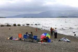 turisté užívající si letní prázdniny u pobřeží jezera Loch Lomond ve Skotsku