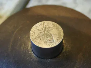 Detail kovové pamětní mince s vyobrazením horníka ve Zlatém dole ve Zlatém Stoku.